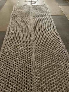 a crocheted table runner sitting on top of a wooden floor