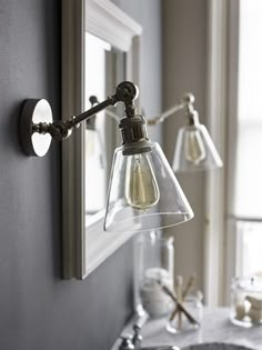 a bathroom with a sink, mirror and two lights on the wall next to it