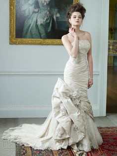 a woman in a wedding dress standing on a rug with her hand under her chin