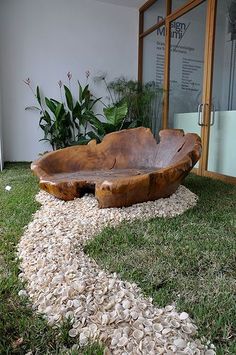 a large wooden bowl sitting on top of a lush green field next to a building