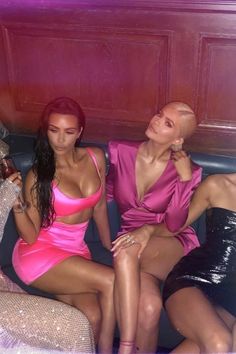 two beautiful women sitting on top of a couch next to each other in pink dresses