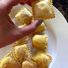 a hand picking up some food from a white plate