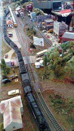 a model train set up on the tracks with buildings and trees in the foreground