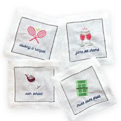 four embroidered napkins with different types of tennis related items on them, all in white