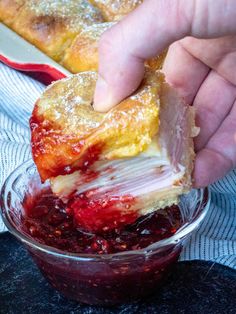 a person dipping jelly into a dessert in a glass bowl on top of a table