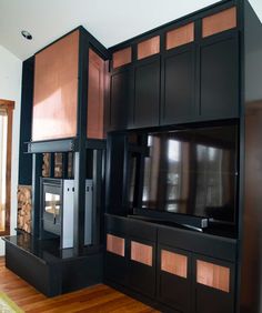 a living room with black cabinets and a flat screen tv mounted to the side of it