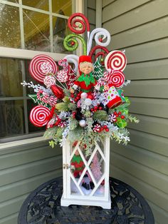 a christmas arrangement on top of a small table with candy canes and greenery