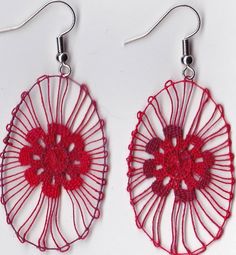 two pairs of red crocheted earrings with metal hooks hanging from them on a white surface