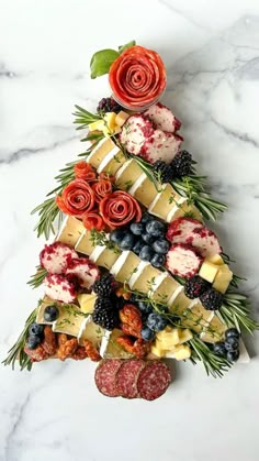 a christmas tree made out of fruits and cheeses on a marble counter top with greenery