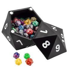 a black dice with white numbers and six different colored dices in the box next to each other