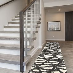 a white staircase with black and white rug on the floor next to it in a house