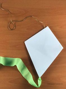 an origami piece of paper with a green ribbon tied around it on a wooden table