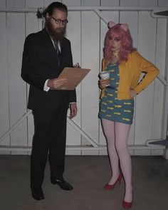 a man and woman dressed in costumes standing next to each other with papers on their laps