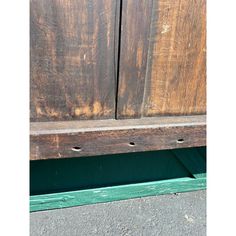 an old wooden bench with two holes in it's side and green paint on the bottom