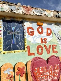 a painted wall with the words god is love written on it and two heart - shaped wooden boards