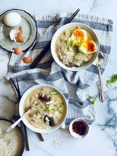 two bowls of oatmeal with an egg on top and spoons next to them