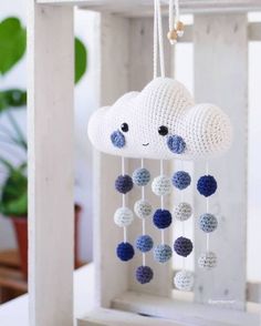 a crocheted cloud mobile with blue and white balls hanging from it's side