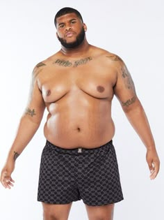 a man with tattoos on his chest and no shirt is posing for the camera while wearing swim trunks