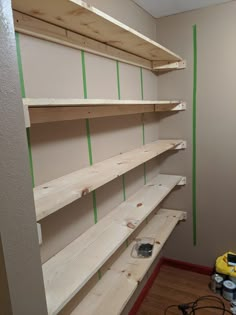 some shelves are being built in the corner of a room with green tape on them