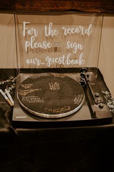 a record player sitting on top of a table next to a sign that says for the record please sign our guest book