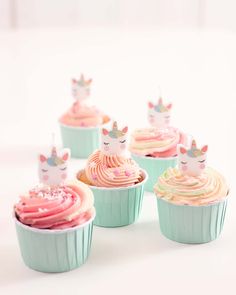 cupcakes decorated with pastel frosting and sprinkles are sitting on a white surface