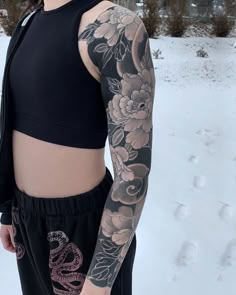 a woman with tattoos standing in the snow