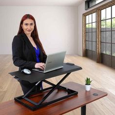 a woman standing at a desk with a laptop on it