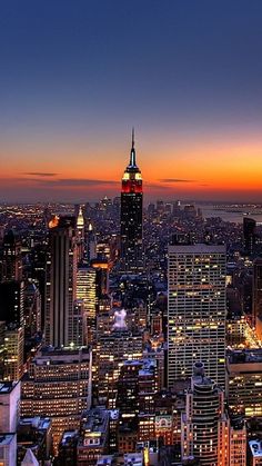 the empire building in new york city at night with lights on and buildings lit up