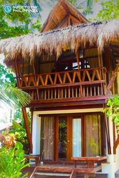 a small house with a thatched roof and wooden steps leading up to the front door