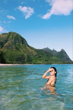 a woman swimming in the ocean with mountains in the background