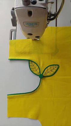 a piece of yellow paper with a green leaf on it next to a sewing machine