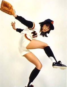 a woman in a baseball uniform holding a catchers mitt while standing on one leg