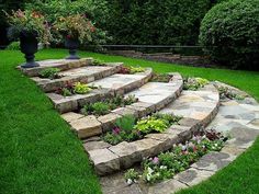 an outdoor garden with stone steps and flowers in the center, surrounded by green grass