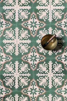 a green and white tiled wall with a brass bell