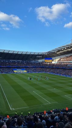 a soccer stadium filled with lots of people on the field and in the stands, there is a blue sky