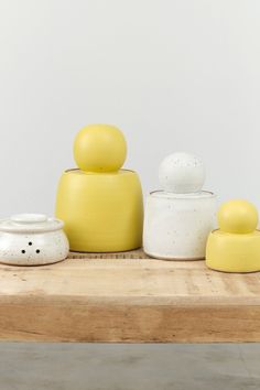 three yellow and white ceramic objects sitting on a wooden table