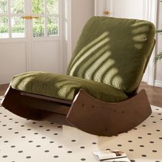 a rocking chair sitting on top of a white floor next to a potted plant