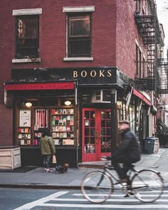 a man riding a bike past a book store