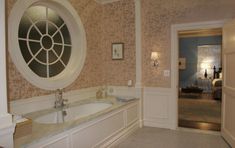 a bathroom with a large tub and round window in it's center wall next to a doorway