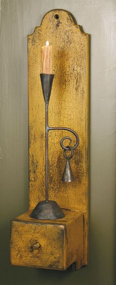 an old fashioned wall mounted candle holder with a small light on it's side