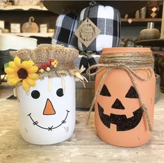 two mason jars decorated with pumpkin faces and sunflowers