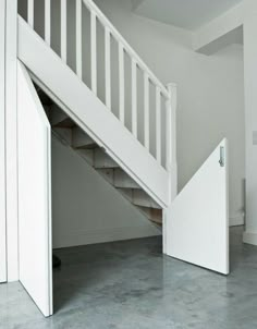 an open door leading to a staircase in a room with white walls and flooring