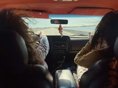 two women sitting in the passenger seat of a car with their hands on the steering wheel