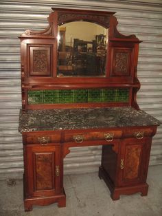 an old wooden desk with a mirror on it's top and green tiles on the bottom