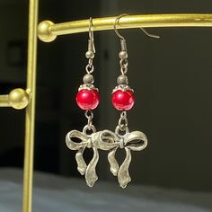 Crafted from my grandmother, Susie, these earrings feature moody red charm and bow. Add a touch of timeless elegance to your jewelry collection with these beautifully crafted earrings. They make a perfect gift for someone special or a delightful treat for yourself. Details: Second image is more accurate coloring Materials: Stainless Steel, red glass pearls Charm: Bow Design: Handmade Style: Elegant and versatile Care Instructions: To keep your earrings looking their best, gently clean with a sof Elegant Christmas Drop Earrings, Elegant Christmas Jewelry With Dangle Shape, Elegant Handmade Earrings For Valentine's Day, Elegant Holiday Earrings For Festive Occasions, Elegant Holiday Jewelry With Matching Earrings, Elegant Festive Holiday Earrings, Elegant Holiday Festive Earrings, Elegant Valentine's Day Holiday Jewelry, Red Dangle Holiday Jewelry