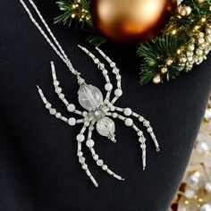 a white spider necklace sitting on top of a black shirt