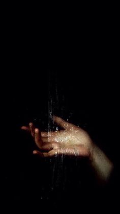 a person's hand reaching for something in the dark with light coming from it