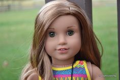 a close up of a doll with long hair and green eyes, wearing a colorful dress