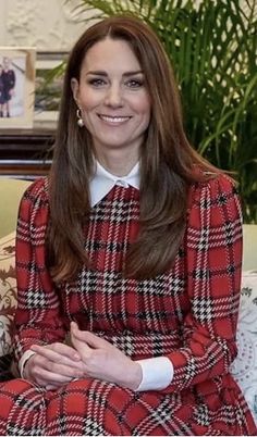 a woman sitting on top of a couch wearing a red plaid dress