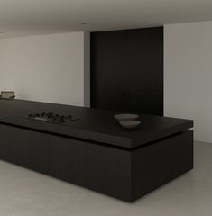 an empty kitchen with black counter tops and white walls in the backround area